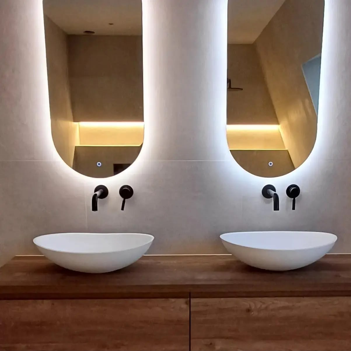 Houten wastafelmeubel met twee witte waskommen en verlichte spiegels